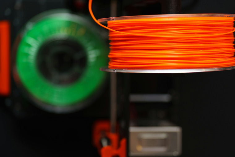 Orange filament spool feeding a 3D printer