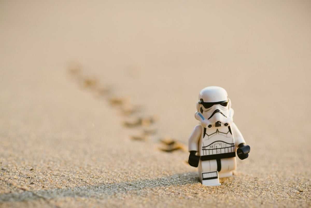 Small plastic building-block figure standing on sand
